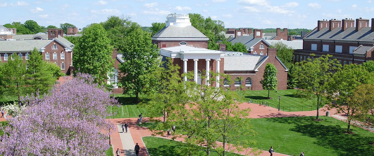 Aerial view of campus in the spring with blooming trees and students walking.